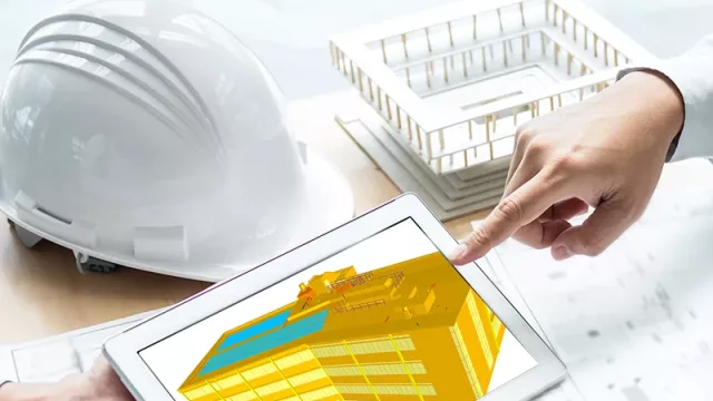 Two people are sitting opposite each other at a table. On the table are a construction helmet, a pocket calculator and various plans. One person holds a tablet that shows a 3D model of a mobile communications station and both people point to the screen.