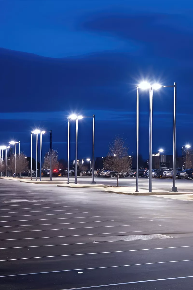 A captivating image displays a tranquil night scene in an empty parking lot, where white lines and softly glowing street lamps create a serene, solitary ambiance. The images low angle and dark asphalt surface draw you into the peaceful stillness.